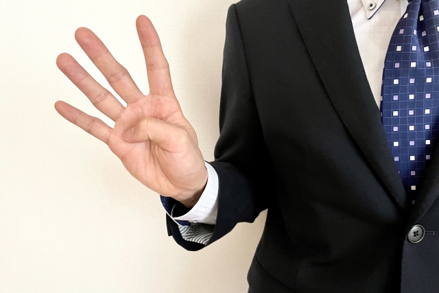 ４つを示すビジネスマンの手元
