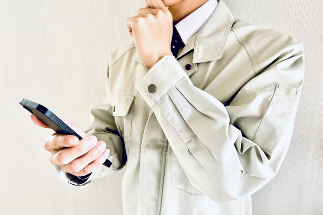 スマホを持って悩んでいる作業員
